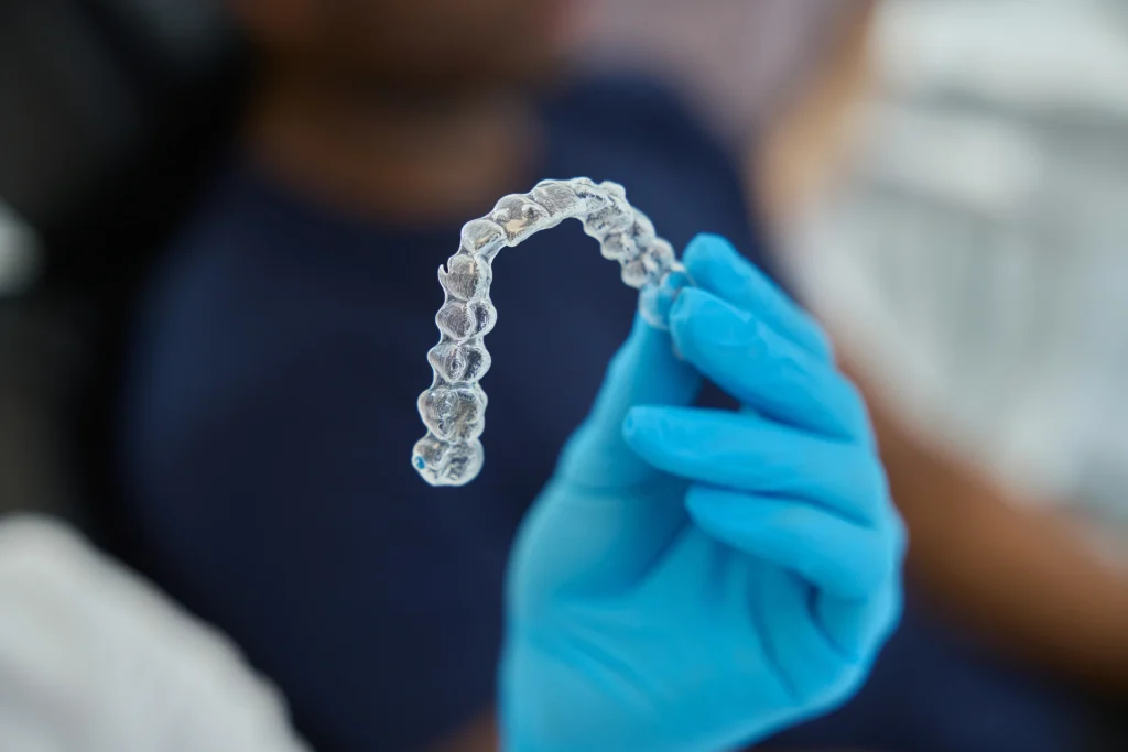 Close-up photo of a dentist holding clear aligners